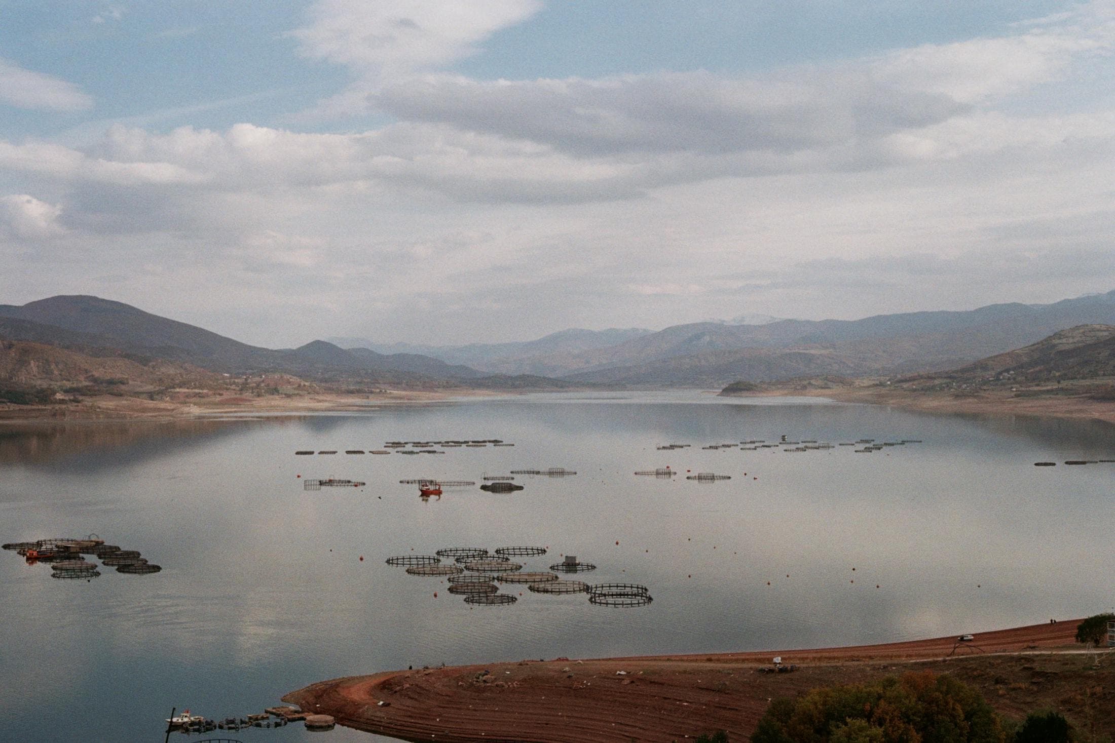 Fish farms on a calm lake surrounded by mountains